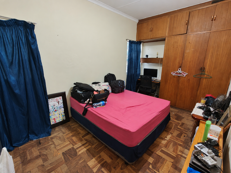 A bedroom featuring parquet flooring and extensive built-in wooden cabinetry with an integrated desk area.
