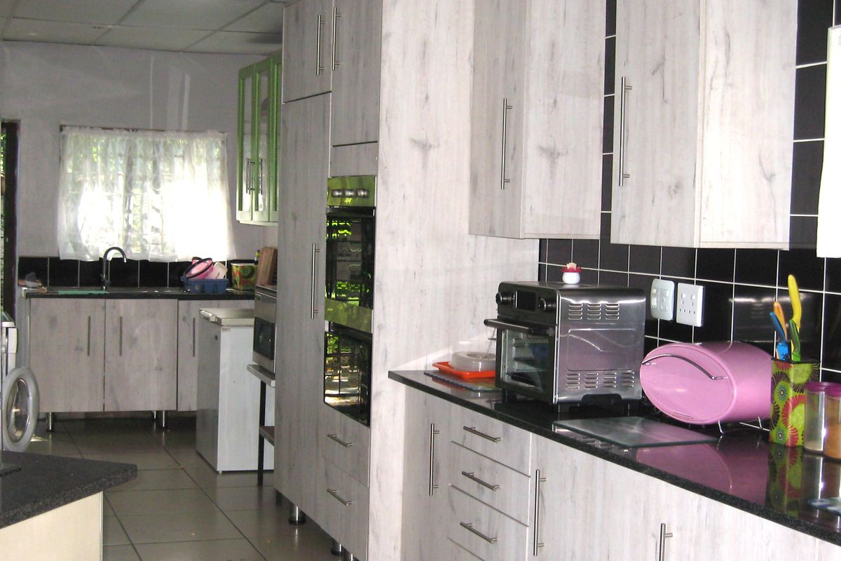 A functional kitchen featuring light wood-grain cabinetry, black granite countertops, a double wall oven, and a tiled backsplash.