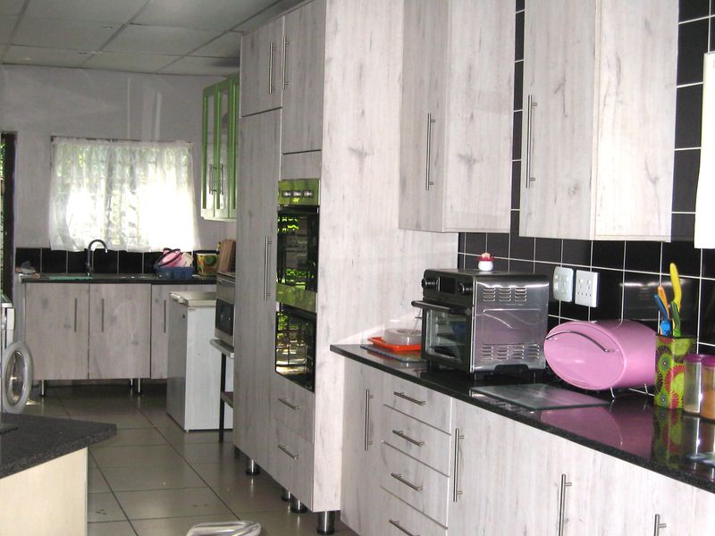 A functional kitchen featuring light wood-grain cabinetry, black granite countertops, a double wall oven, and a tiled backsplash.