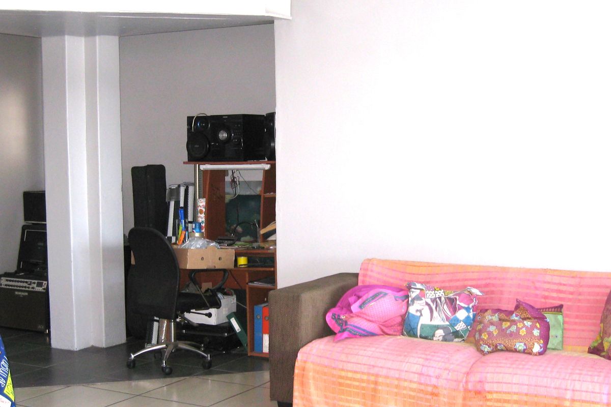 A living area featuring tiled flooring and a structural column, providing an open layout suitable for various furniture arrangements.