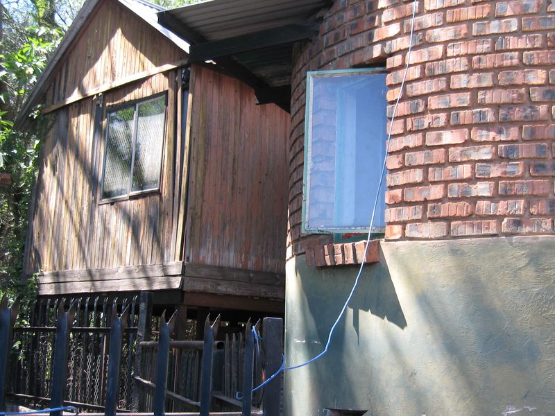 Exterior view showing a combination of timber-clad structure and curved brick masonry with visible weathering and maintenance requirements.
