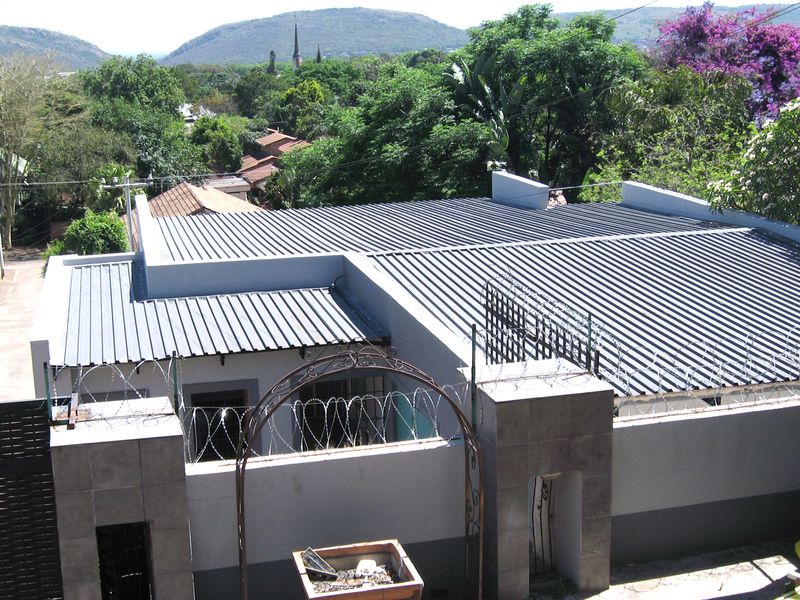 Aerial view of the property showing the corrugated metal roof, perimeter wall with security razor wire, and a decorative metal entrance archway.