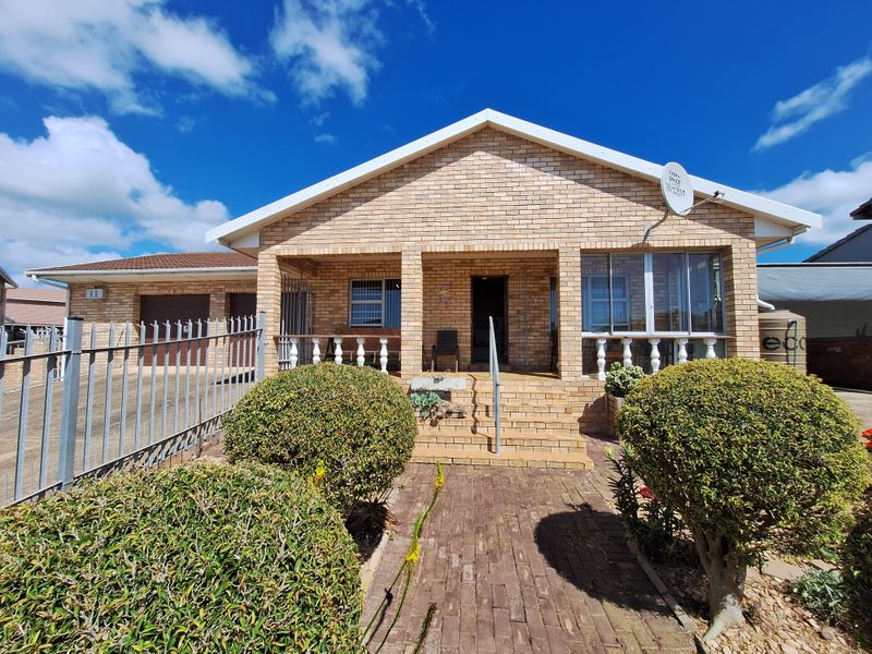 Front view of a face brick house featuring a covered porch with concrete balustrades, a paved walkway, and an attached garage.