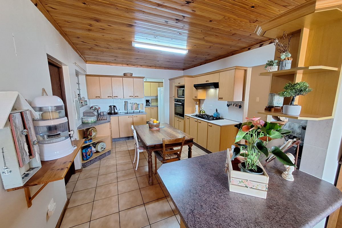 Spacious kitchen featuring timber ceiling, built-in cabinetry, gas hob, and integrated oven, offering a functional layout with ample storage and workspace.