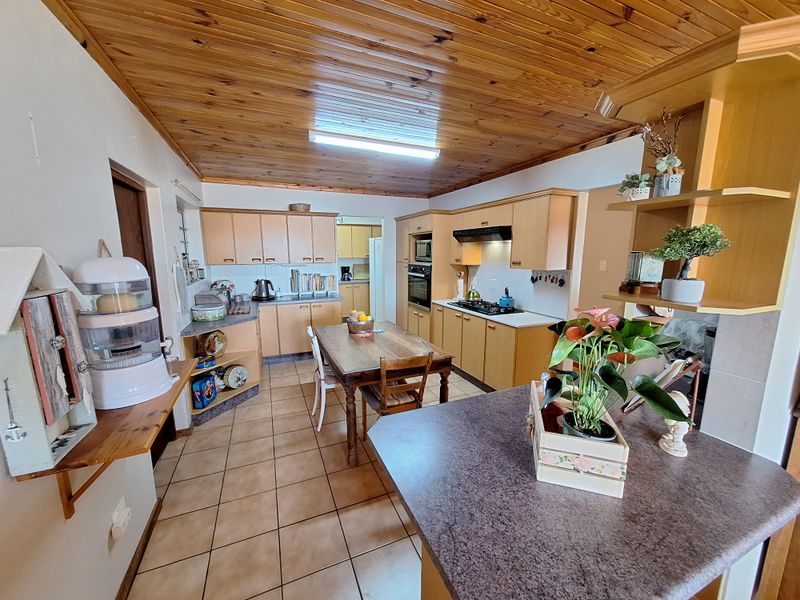 Spacious kitchen featuring timber ceiling, built-in cabinetry, gas hob, and integrated oven, offering a functional layout with ample storage and workspace.