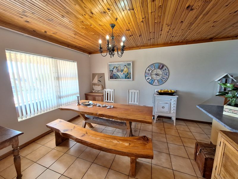 A dining area featuring a timber tongue and groove ceiling, ceramic floor tiles, and a wrought iron chandelier, providing a rustic aesthetic.