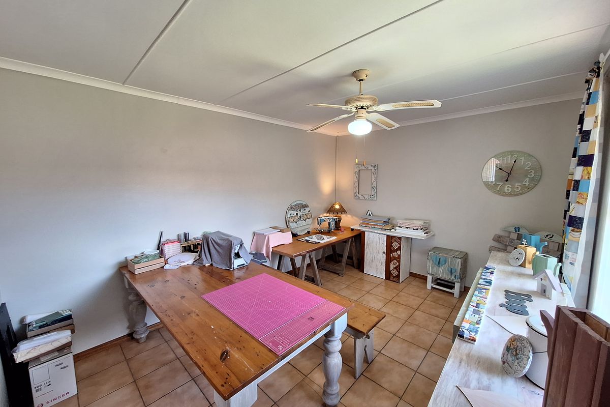 A versatile room featuring tiled flooring and a ceiling fan, currently utilized as a craft space but suitable for a bedroom or home office.