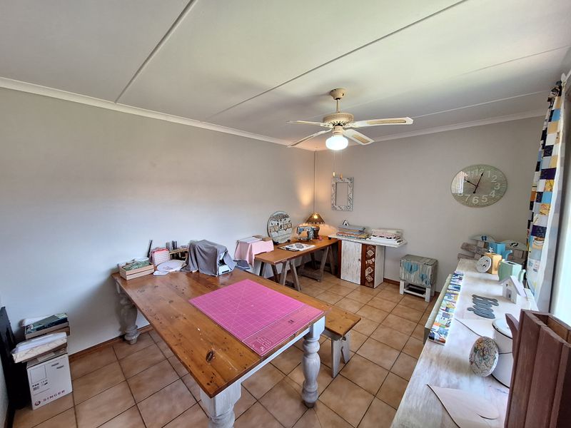 A versatile room featuring tiled flooring and a ceiling fan, currently utilized as a craft space but suitable for a bedroom or home office.