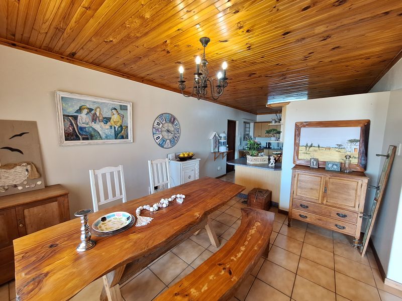 Open plan dining and kitchen area featuring warm timber tongue and groove ceilings, ceramic tiled flooring, and a functional breakfast bar.