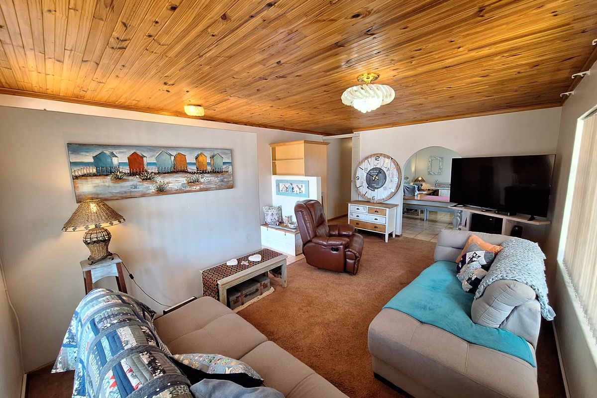 A living room featuring a distinctive timber tongue and groove ceiling, carpeted flooring, and an arched entryway leading to an adjacent space.