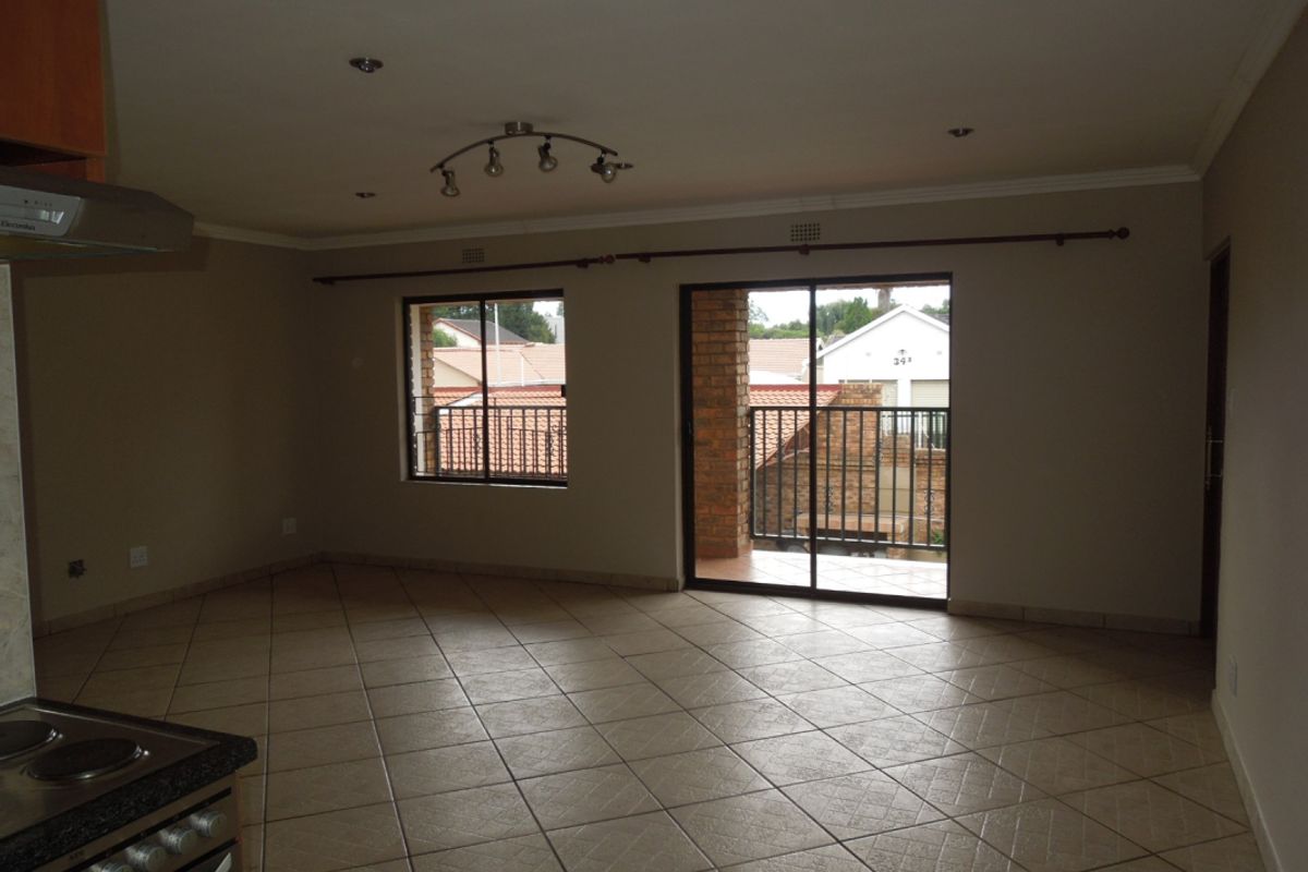 Spacious open-plan living area featuring tiled flooring, recessed lighting, and direct access to a private balcony through sliding glass doors.