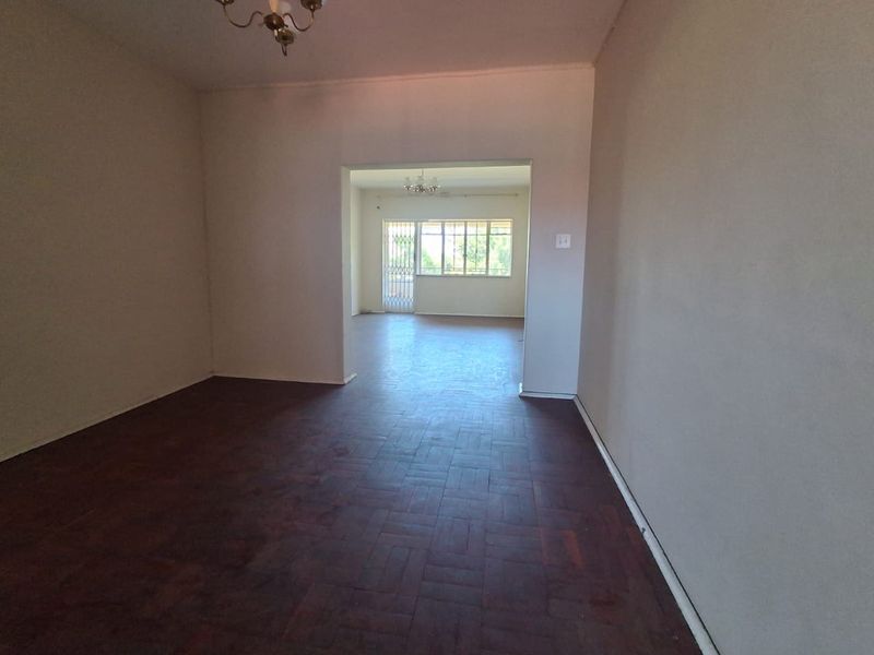 Spacious open-plan living area featuring traditional parquet flooring and natural light, providing a versatile blank canvas for modern interior design.