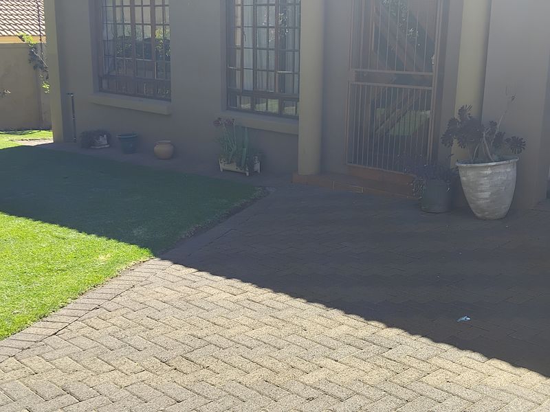 Front exterior view of the townhouse featuring a paved driveway, small lawn area, and secure entrance with a security gate.