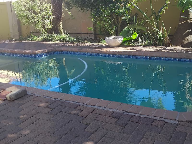 A private swimming pool area featuring brick paving surround and a perimeter boundary wall, offering a functional outdoor space for relaxation.