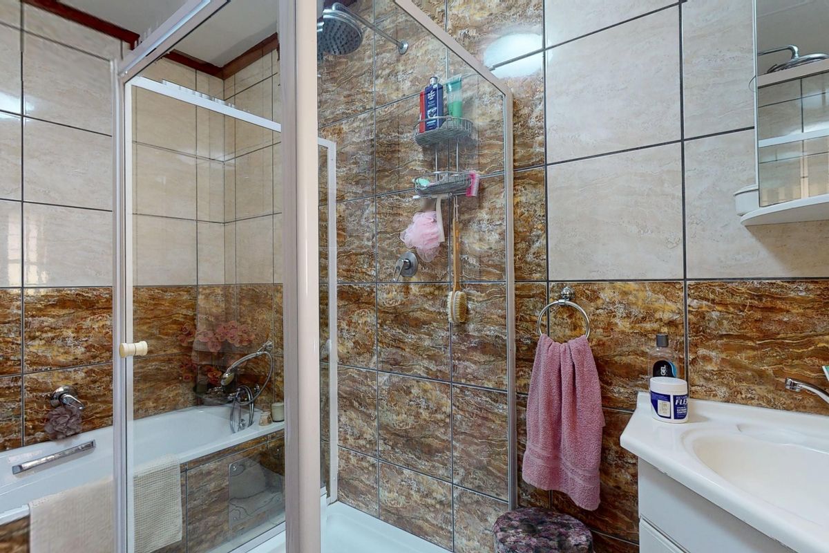 A functional bathroom featuring a separate shower enclosure, bathtub, and vanity basin with tiled wall finishes.