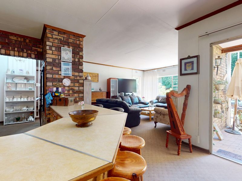 Open plan living area featuring an exposed brick pillar, breakfast bar, and direct access to an outdoor patio through sliding glass doors.