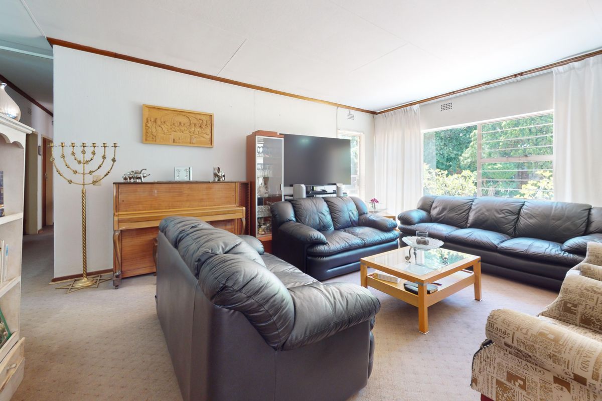 A spacious living room featuring large windows that provide natural light and carpeted flooring throughout.