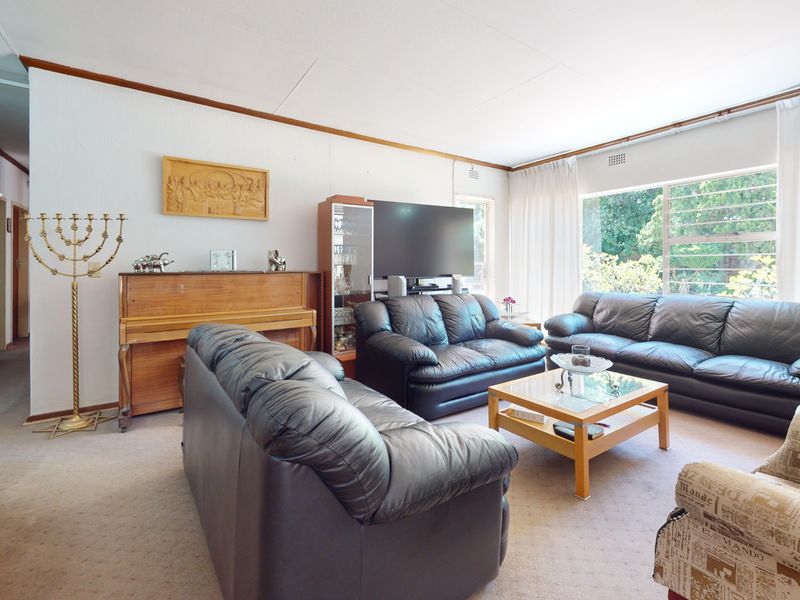 A spacious living room featuring large windows that provide natural light and carpeted flooring throughout.