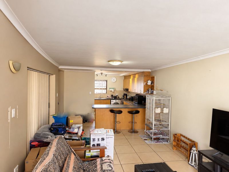 Open plan living and kitchen area featuring tiled flooring, breakfast bar, and built-in cabinetry, offering a functional layout for modern apartment living.