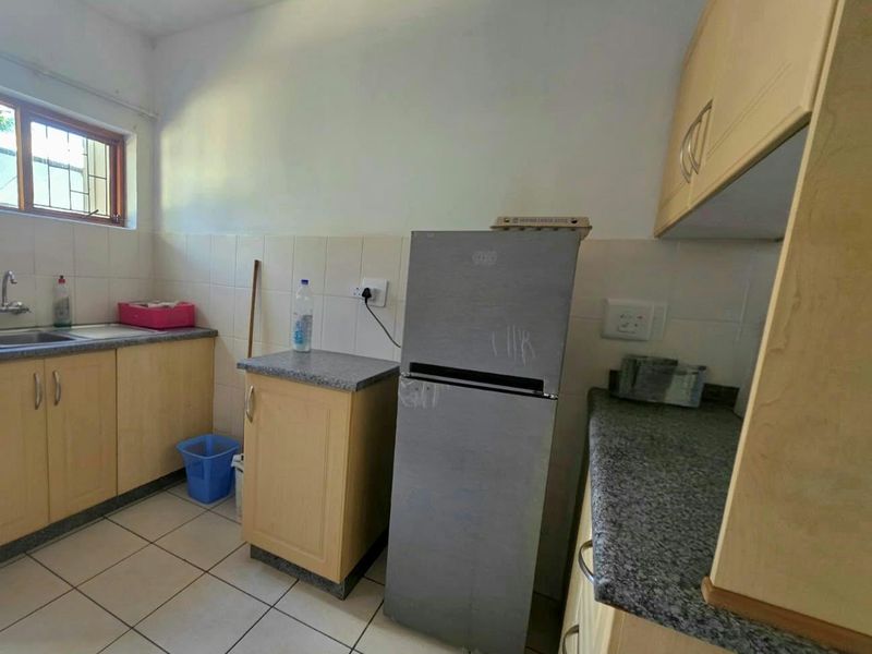 A functional kitchen featuring laminate cabinetry, granite countertops, tiled backsplash, and tiled flooring, offering a practical layout for daily meal preparation.
