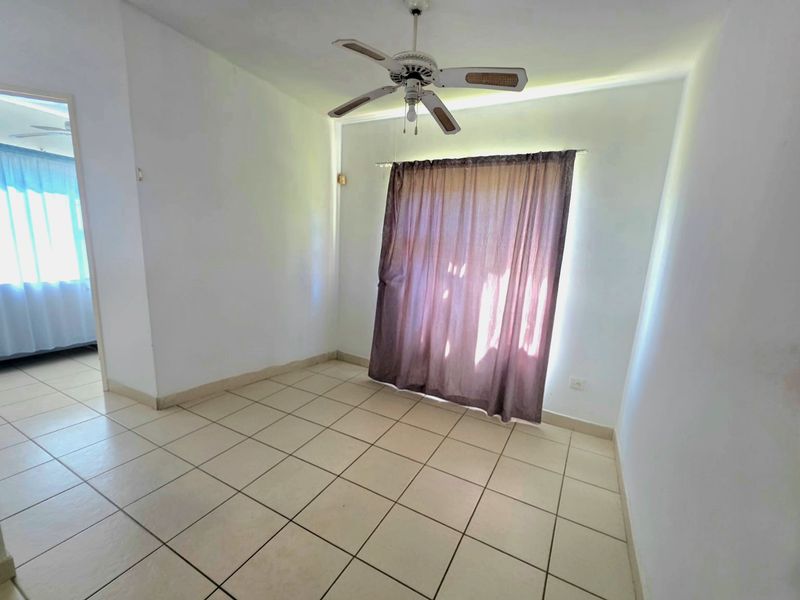 An empty bedroom featuring neutral tiled flooring, a ceiling fan, and a window with a curtain rod.