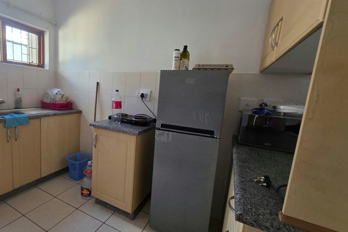 A functional kitchen featuring laminate cabinetry, granite countertops, and tiled flooring. The space offers a practical layout with a built-in hob and sink area.