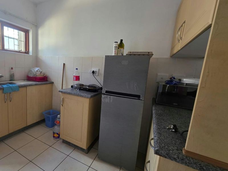 A functional kitchen featuring laminate cabinetry, granite countertops, and tiled flooring. The space offers a practical layout with a built-in hob and sink area.