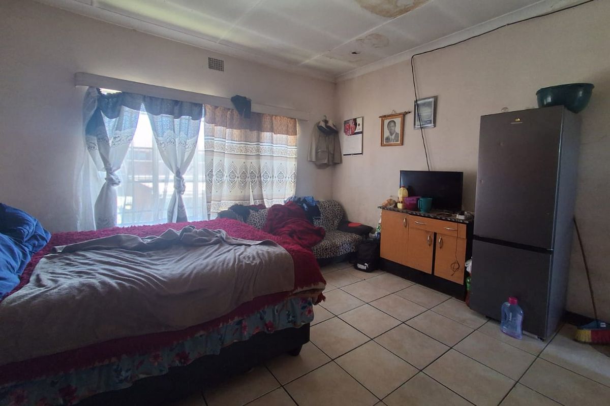 A bedroom featuring tiled flooring and visible ceiling water damage, requiring maintenance and cosmetic updates to improve the overall condition.