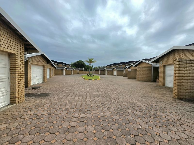 A view of the townhouse complex driveway featuring brick facades, multiple garage doors, and paved surfacing.
