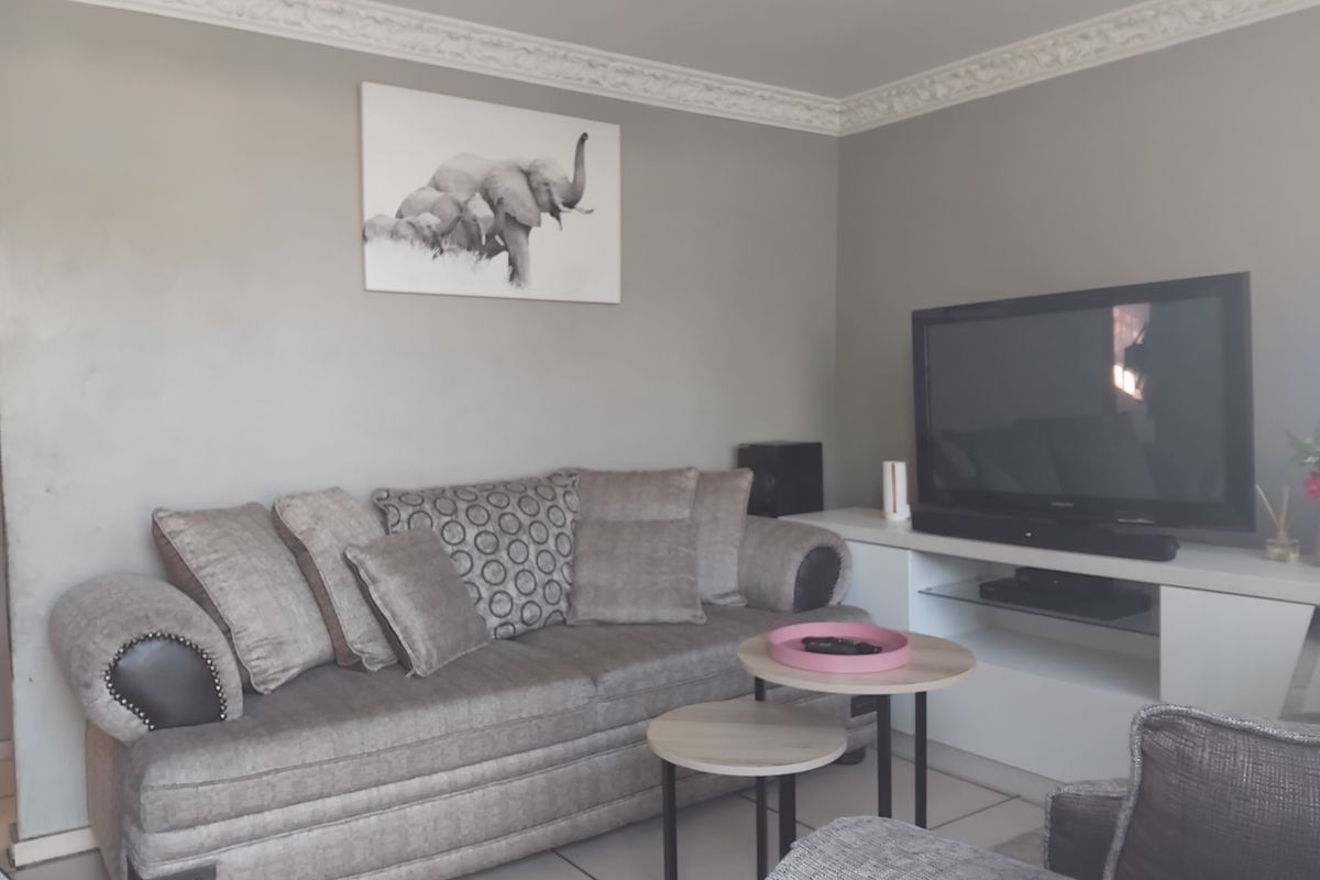 A comfortable living room featuring decorative ceiling cornicing and neutral tiled flooring, providing a solid foundation for modern interior updates.
