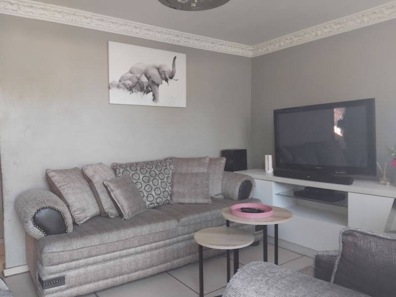 A comfortable living room featuring decorative ceiling cornicing and neutral tiled flooring, providing a solid foundation for modern interior updates.