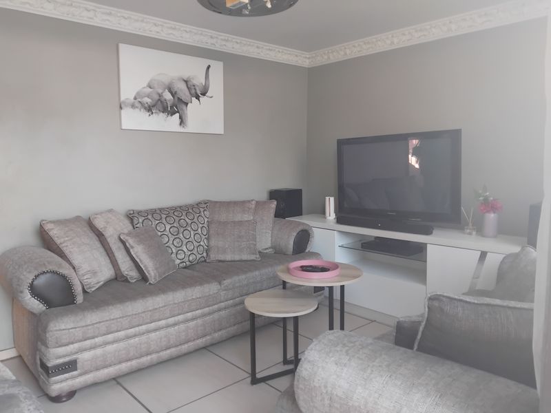 A comfortable living room featuring tiled flooring and decorative ceiling cornicing, providing a neutral base for personalization.
