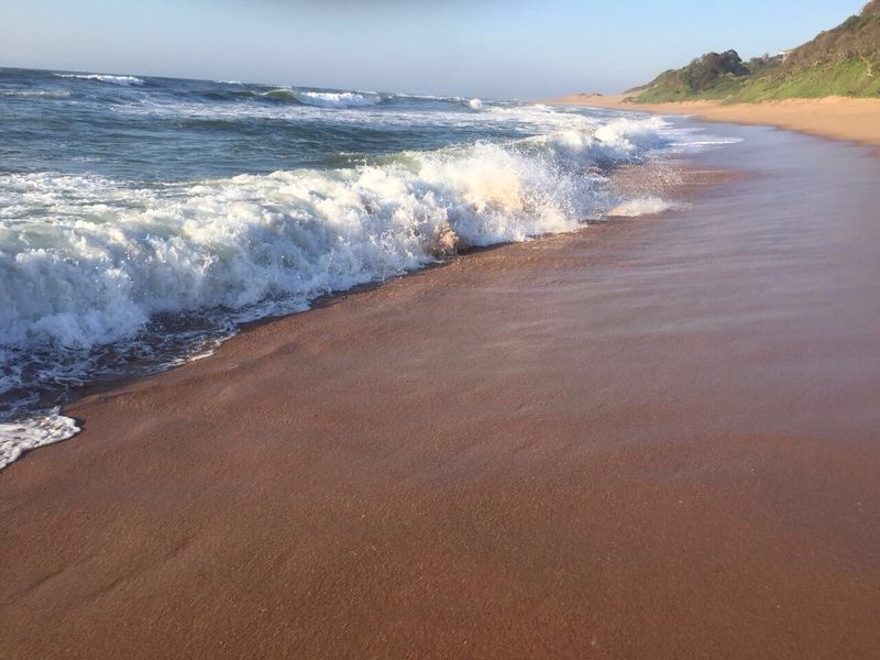 A scenic view of the coastline featuring sandy beach and ocean waves.