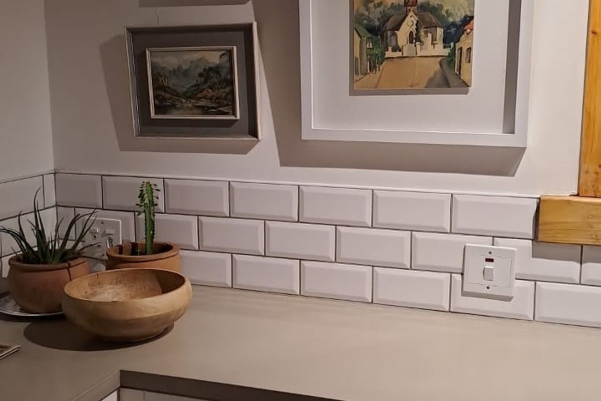 A well-maintained kitchen corner featuring white shaker-style cabinetry, a neutral countertop, and a classic white subway tile backsplash.