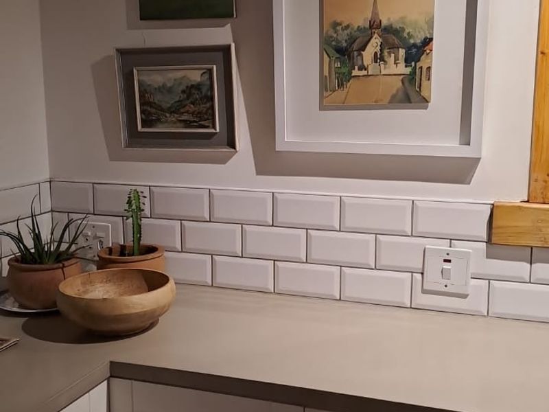 A well-maintained kitchen corner featuring white shaker-style cabinetry, a neutral countertop, and a classic white subway tile backsplash.