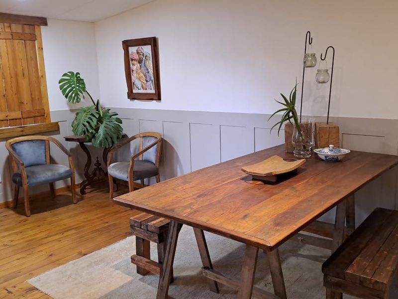 A dining room featuring warm timber flooring, classic timber shutters, and decorative wainscoting, creating a cozy and traditional atmosphere.