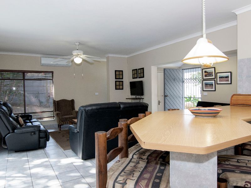 Open-plan living area featuring tiled floors, a breakfast bar with pendant lighting, and a split-system air conditioner, providing a functional and connected living space.