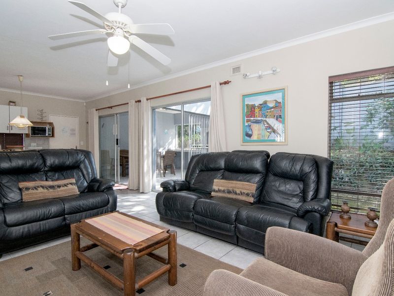 Open plan living area featuring tiled floors, a ceiling fan, and sliding glass doors providing access to the outdoor patio area.