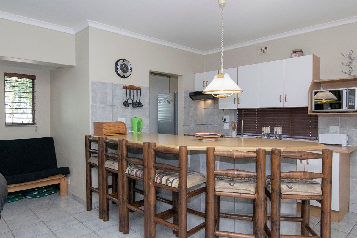 A functional kitchen featuring a breakfast bar, built-in cabinetry, tiled backsplash, and integrated appliances, offering a practical layout for daily use.