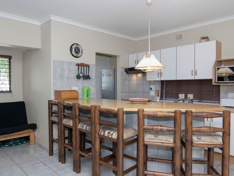A functional kitchen featuring a breakfast bar, built-in cabinetry, tiled backsplash, and integrated appliances, offering a practical layout for daily use.