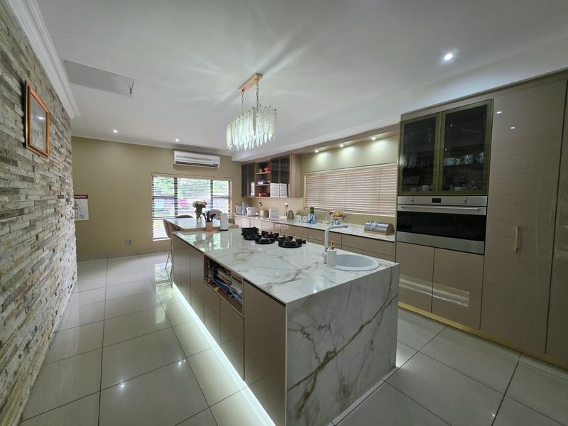 Modern kitchen featuring a large marble-look island with gas hob, integrated cabinetry, built-in oven, and a striking stone feature wall.