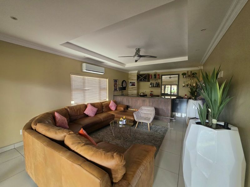Spacious living room featuring a built-in bar, recessed ceiling with fan, split-system air conditioning, and large format floor tiles.