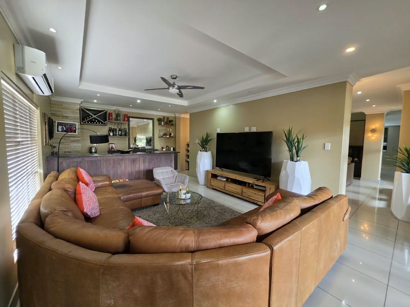 Spacious living room featuring a built-in bar, recessed ceiling with downlights, ceiling fan, and tiled flooring, creating a comfortable and functional entertainment area.