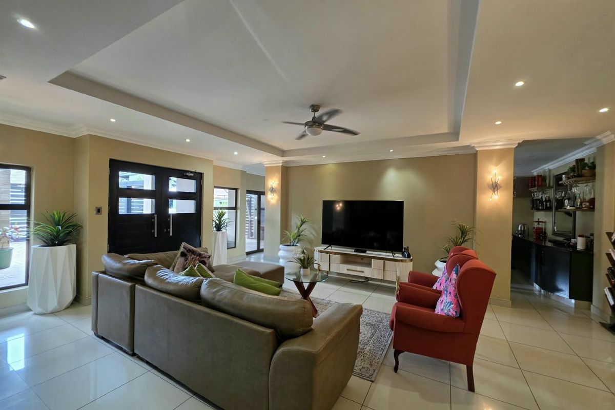 Spacious living room featuring a recessed ceiling with downlights, a ceiling fan, and polished tiled flooring, creating a bright and open atmosphere.