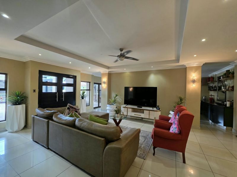 Spacious living room featuring a recessed ceiling with downlights, a ceiling fan, and polished tiled flooring, creating a bright and open atmosphere.