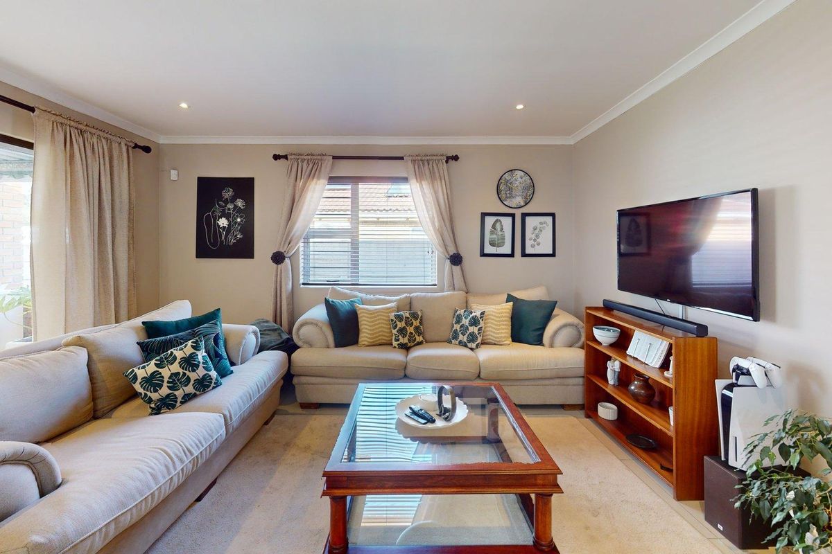 A comfortable living room featuring recessed downlights, neutral wall finishes, and a sliding glass door providing access to the outdoor area.
