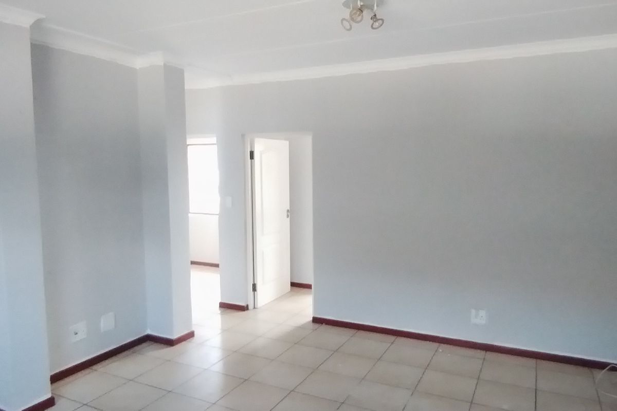 An empty, neutrally painted living area featuring tiled flooring and clean architectural lines, providing a versatile blank canvas for interior design.