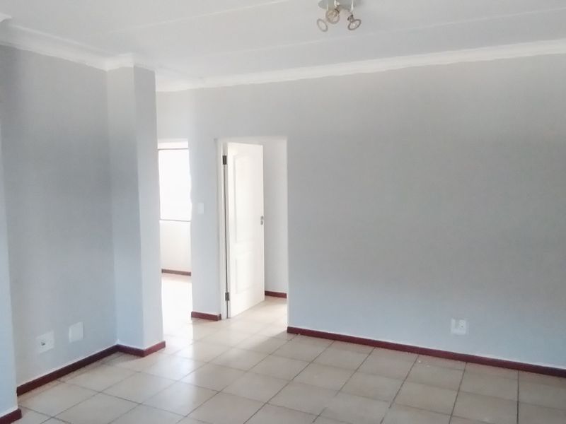 An empty, neutrally painted living area featuring tiled flooring and clean architectural lines, providing a versatile blank canvas for interior design.