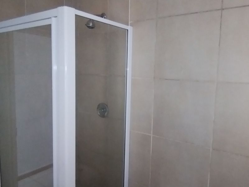 A functional bathroom featuring a corner shower enclosure with tiled walls and standard fixtures.
