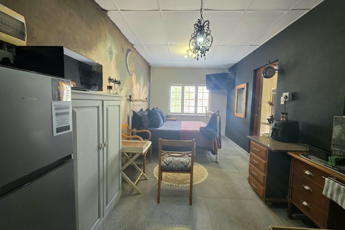 A bedroom featuring tiled flooring, ceiling tiles, and window shutters. The space includes a decorative wall mural and requires cosmetic updates to finishes.